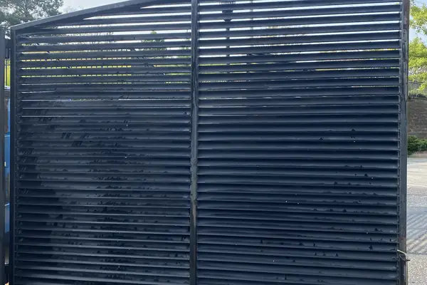 Louvered metal dumpster enclosure gate at a shopping center in Suwanee, GA, after washing