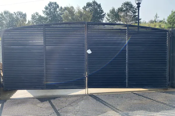 Arched metal dumpster enclosure gates at a shopping center in Suwanee, GA, clean after the morning wash