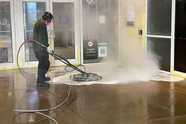 Georgia Bubbles crew member running a hot-water surface cleaner at a mall entrance in Atlanta at night