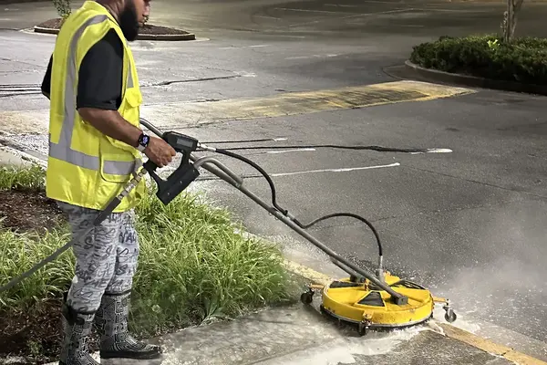 Georgia Bubbles crew member running a surface cleaner along the curb at a shopping center in Duluth, GA, at night
